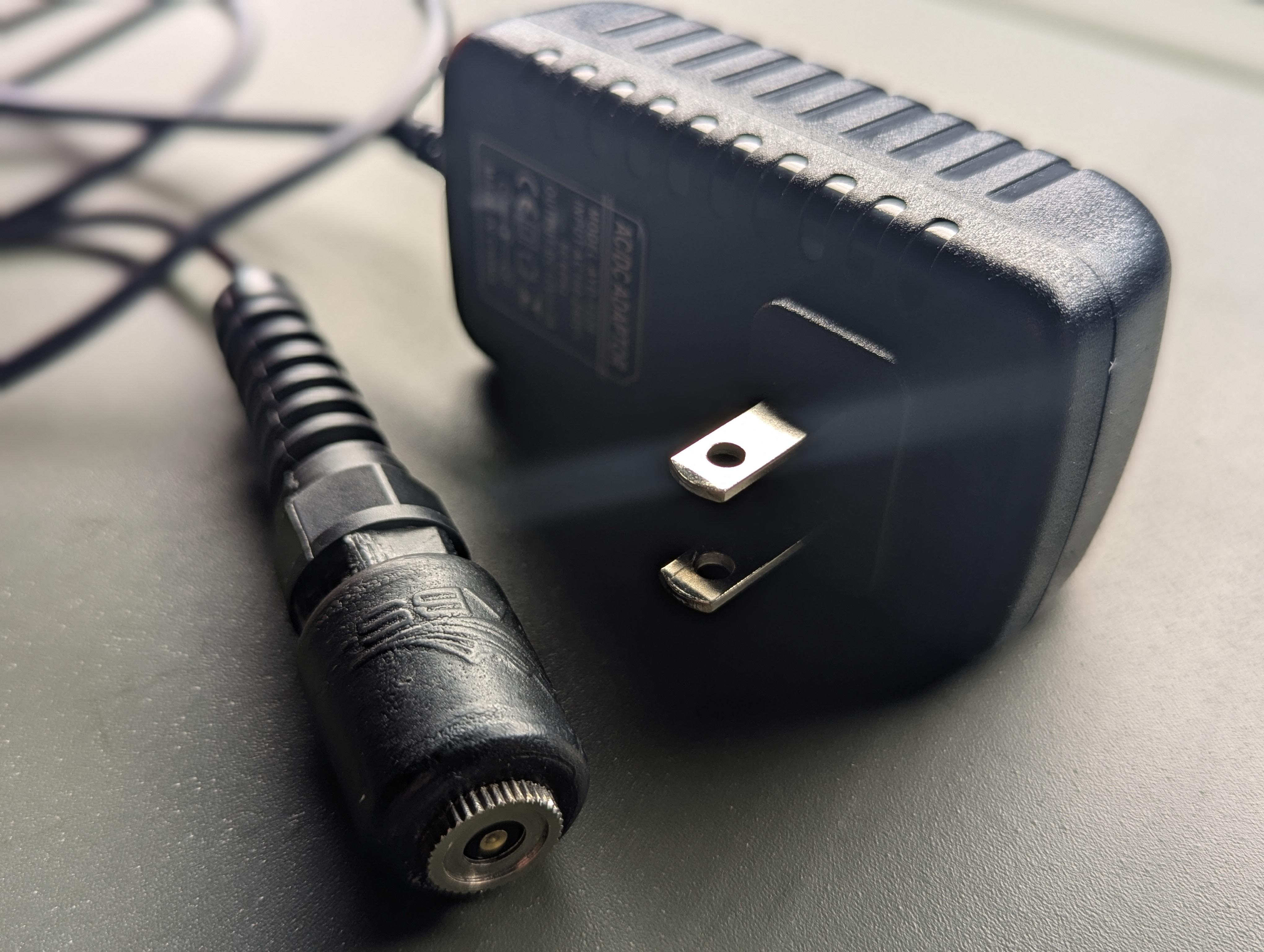 RC-1 wall adapter with US plug prongs extended, alongside the charger's connector end