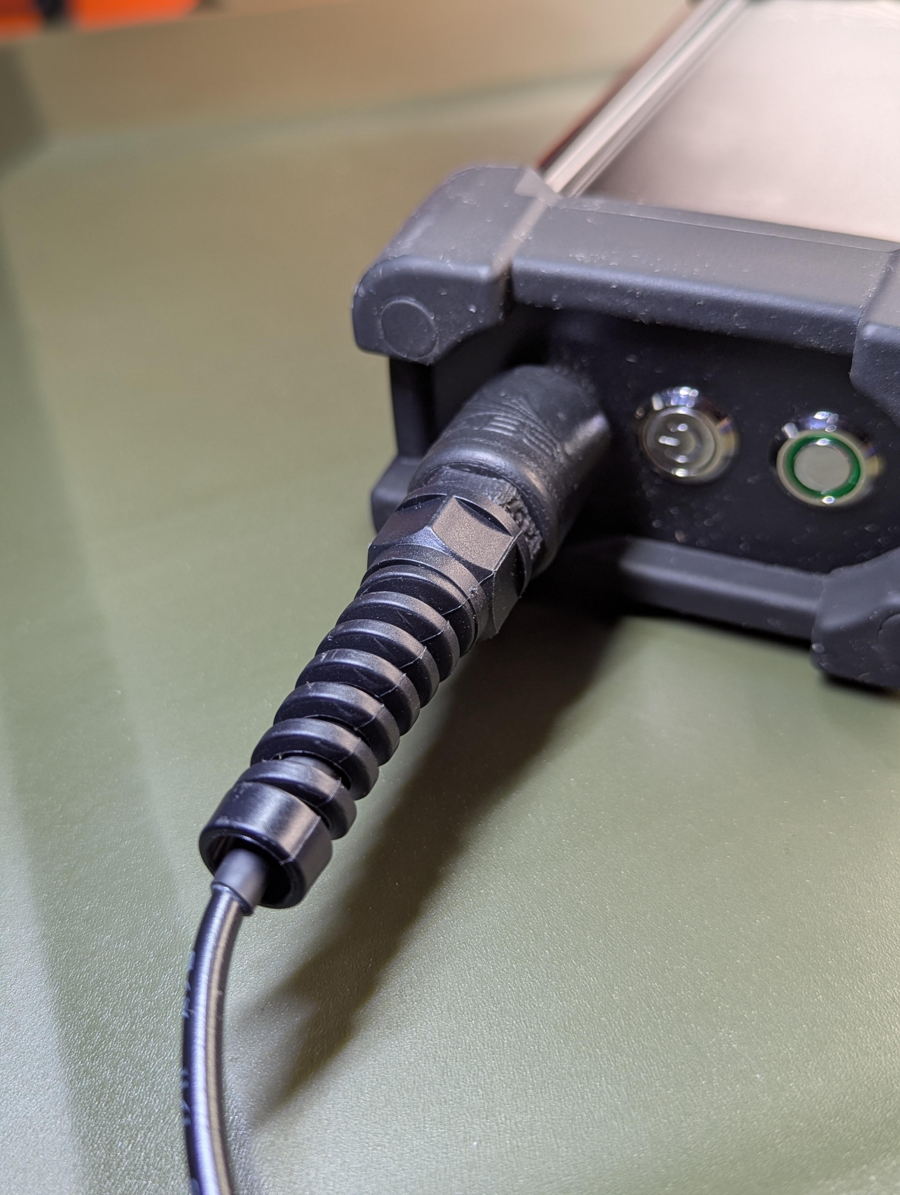 RC-2 charger seated on the end panel of an AT Labs RM-1/RM-2 radio, barrel input facing out beside the power and status buttons